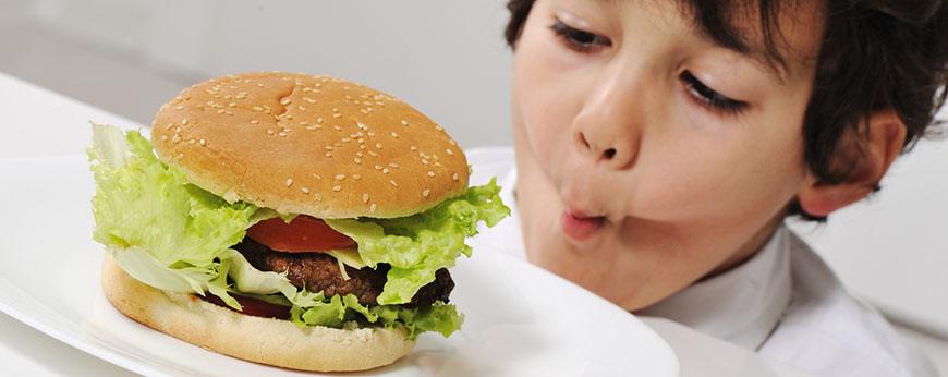 Kid on temptation with delicious hamburger
