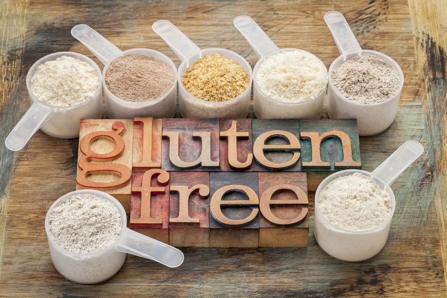 czy-produkty-bezglutenowe-sa-zdrowe1.jpg measuring scoops of gluten free flours (almond, coconut, teff, flaxseed meal, whole rice, brown rice, buckwheat) wit a text in letterpress wood type